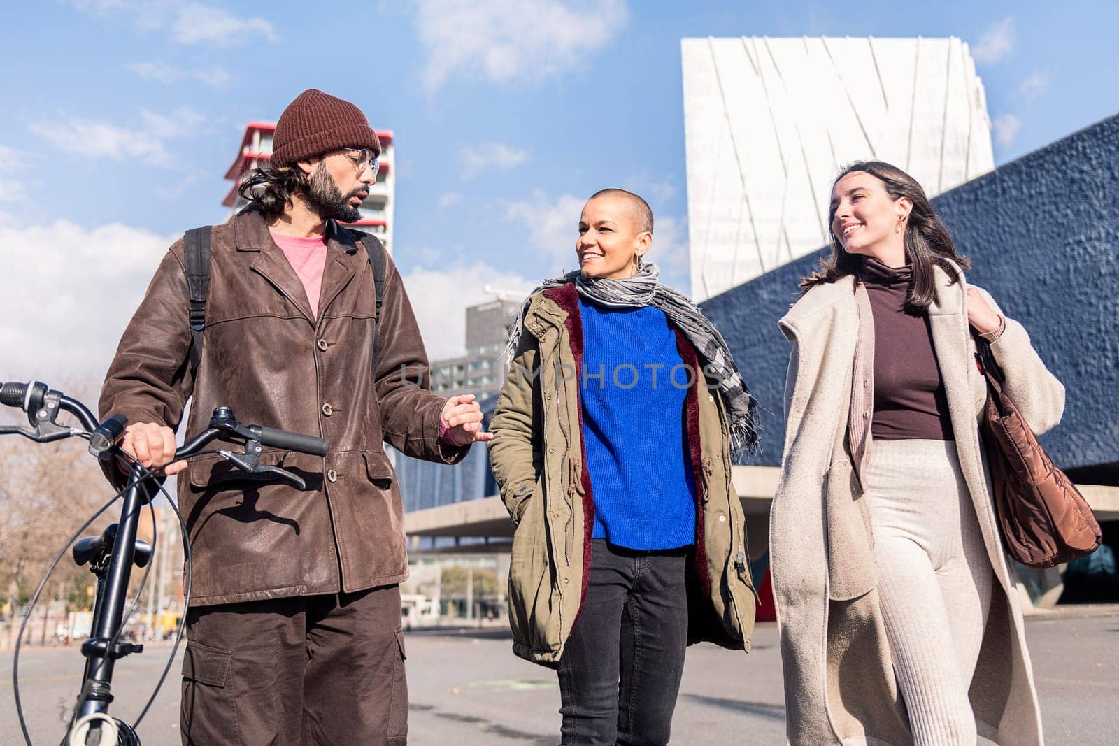 three young friends talking happy while strolling through the city, concept of friendship and modern urban lifestyle