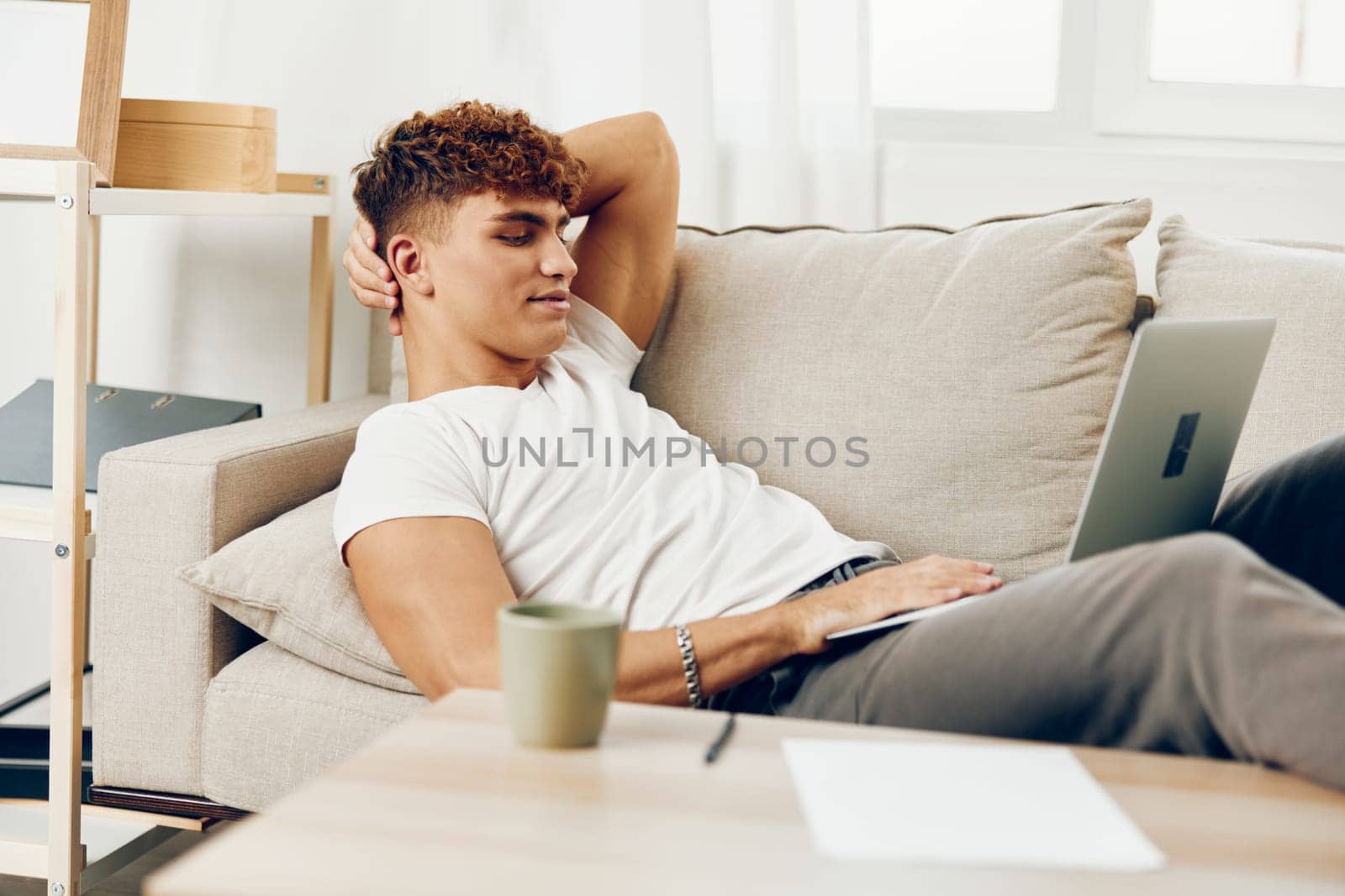man interior t-shirt couch home male freelance student call chat by SHOTPRIME