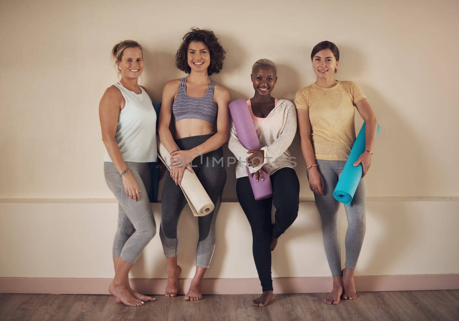 We love doing yoga together. Full length portrait of a young group of woman sitting together and bonding during an indoor yoga session. by YuriArcurs