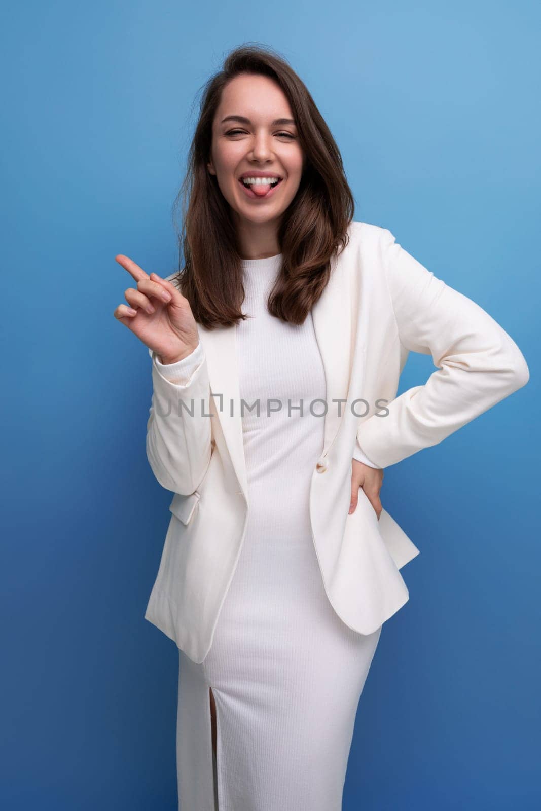 cheerful positive brunette woman in white dress posing as model on studio background.