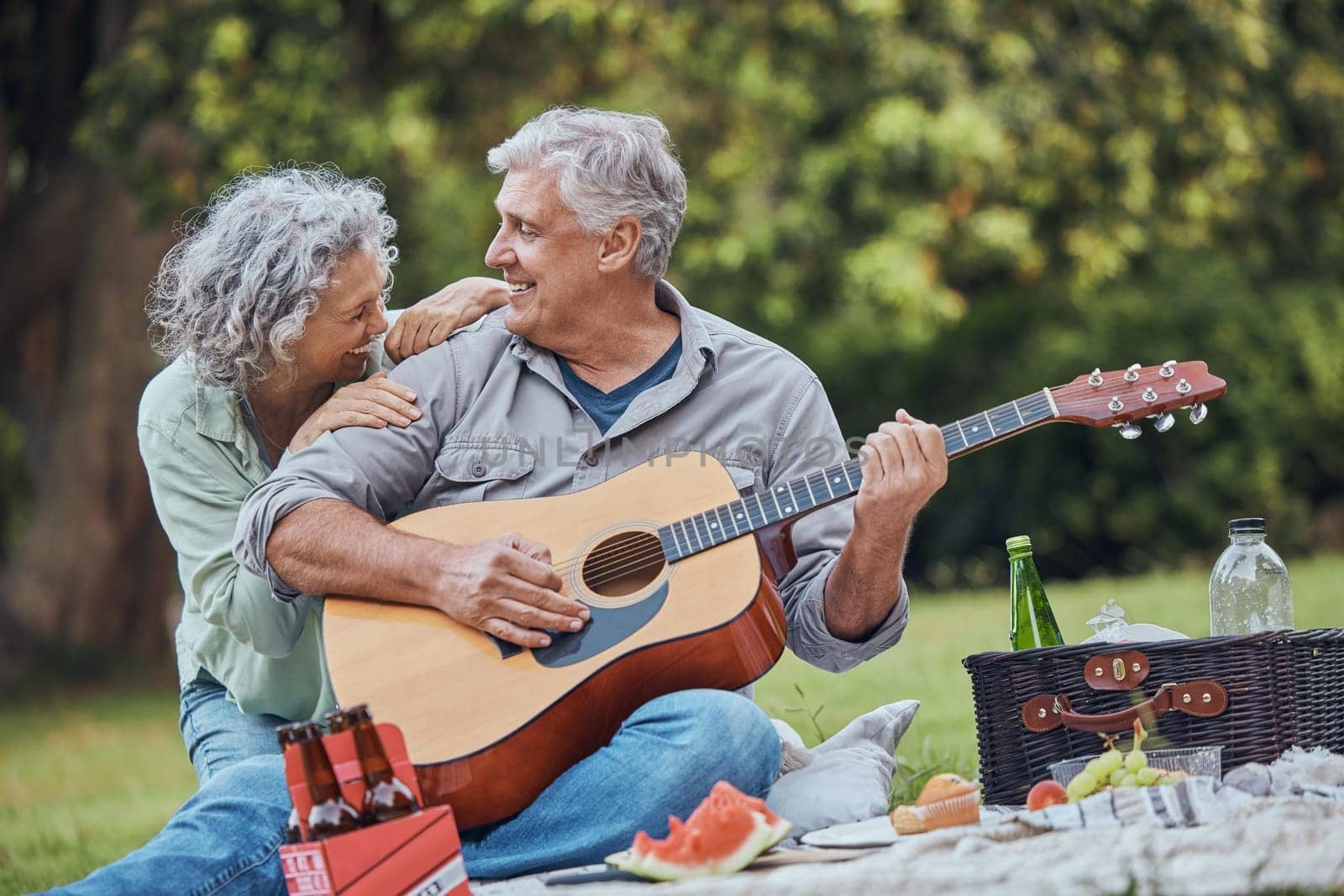 Music, guitar and a senior couple on picnic in park laughing with food, drinks and romance in retirement. Nature, love and elderly man and happy woman on romantic date on the grass on summer weekend. by YuriArcurs