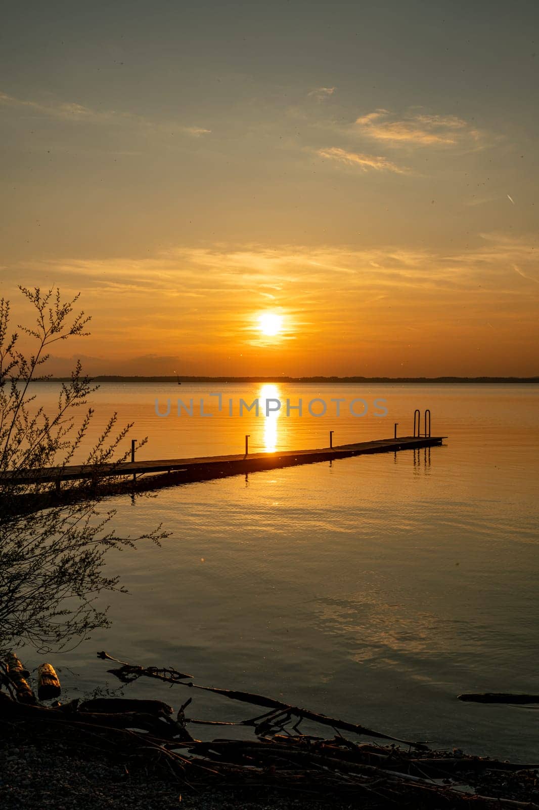 a beautiful sunset over the chiemsee in Bavaria in Germany with a wooden platform in the foreground