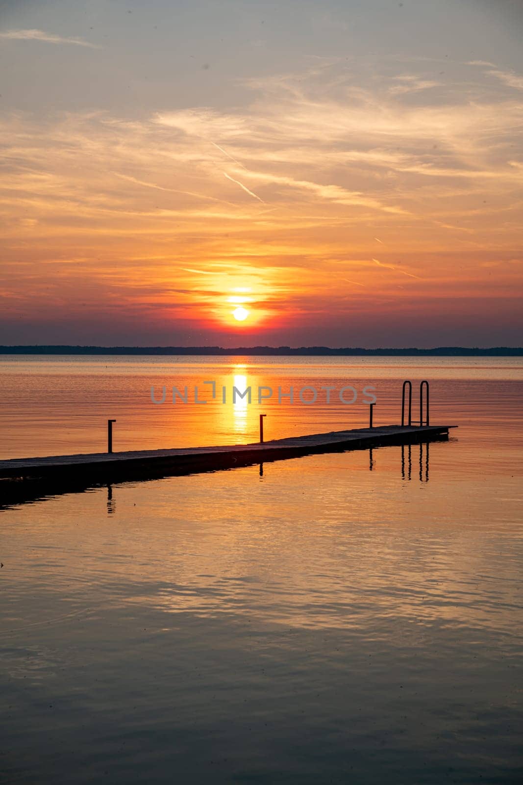 a beautiful sunset over the chiemsee in Bavaria in Germany with a wooden platform in the foreground