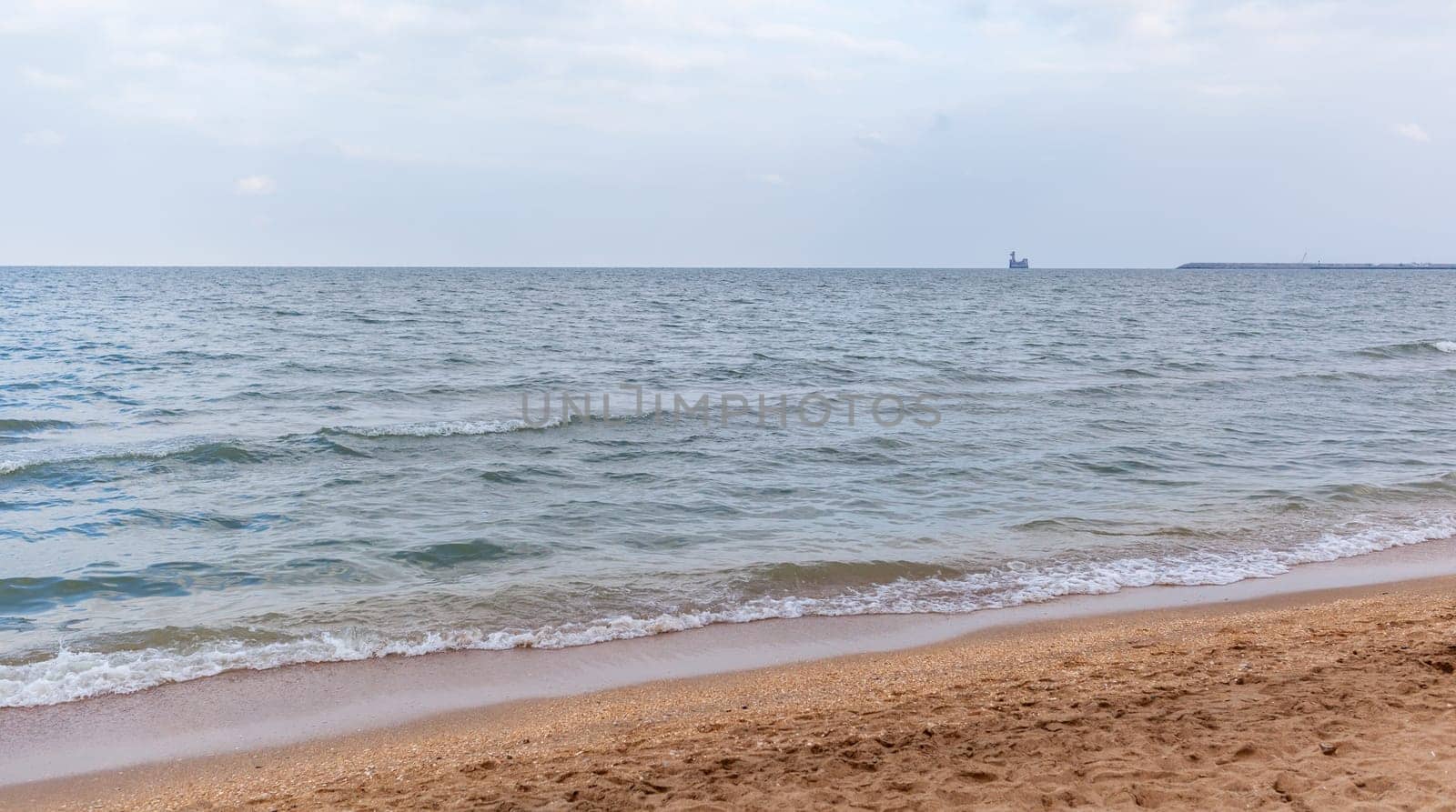 The waves of the sea roll on the sandy shore on a cloudy day. A storm or storm is coming. Rest and walk on the sea