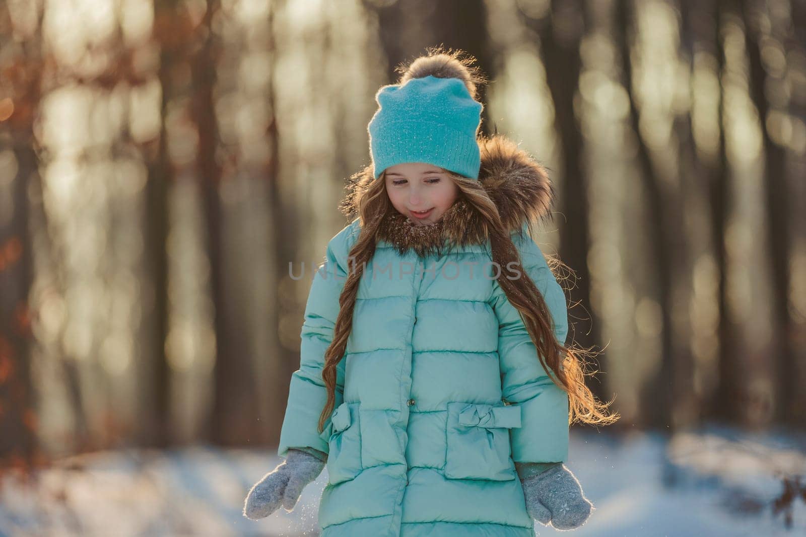 portrait of a girl against the backdrop of a winter forest illuminated by the sun