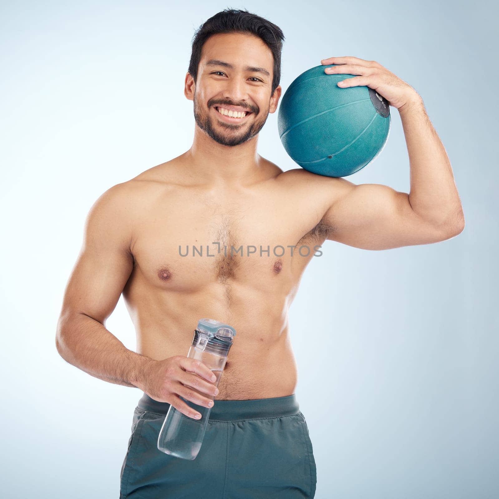 Fitness, portrait and medicine ball with a sports man in studio for health or natural body. Water bottle, face and exercise with a male athlete training for a healthy lifestyle with gym equipment by YuriArcurs