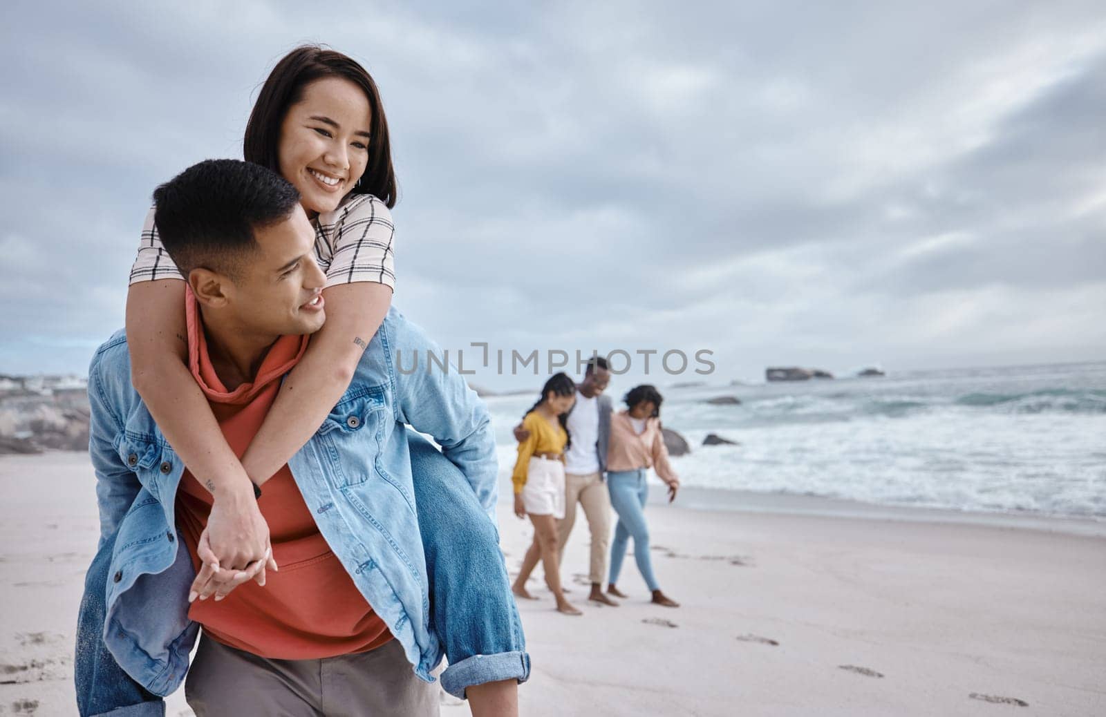 Happy, piggyback or couple of friends at a beach on a relaxing holiday vacation bonding in nature together. Love, man and Asian woman with smile at sea enjoys traveling on ocean trips in Miami, USA.