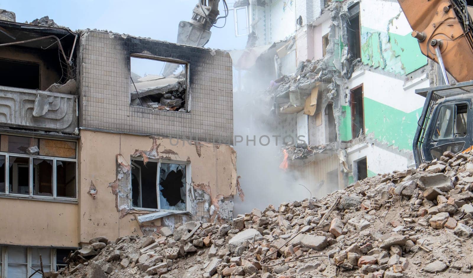 The process of demolition of the old dismantling of the building. The excavator breaks the house. Demolition of dilapidated housing. Construction digger demolishing a house for renovation