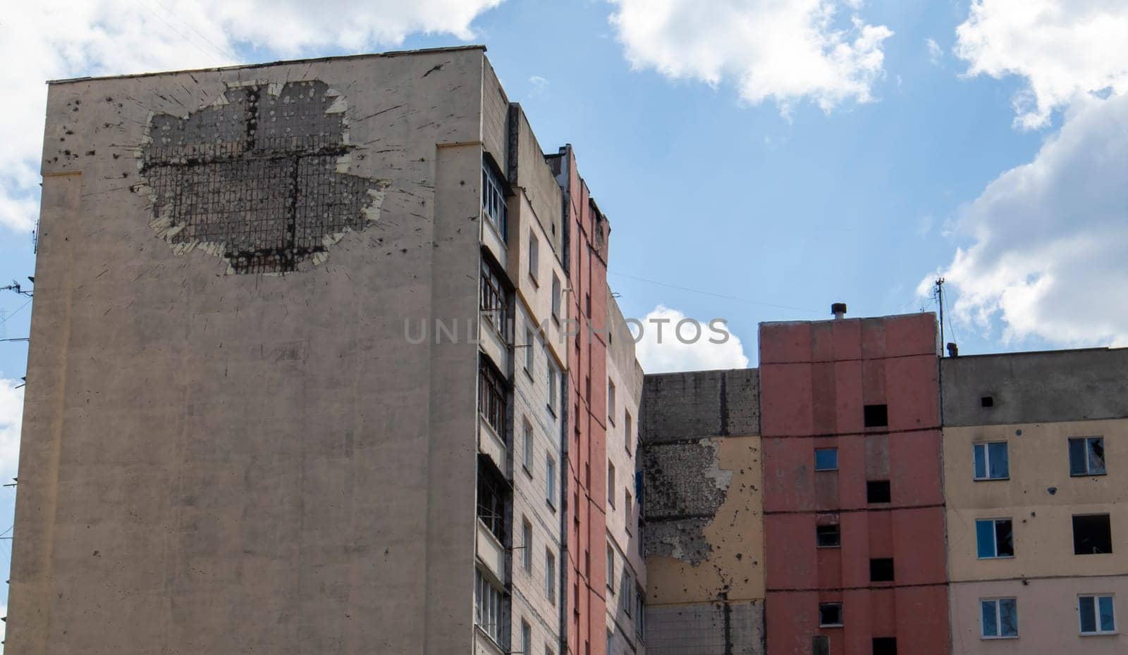 Traces of an artillery shell hitting a multi-storey residential building. Shelling at home. Consequences of the occupation and hostilities in the city