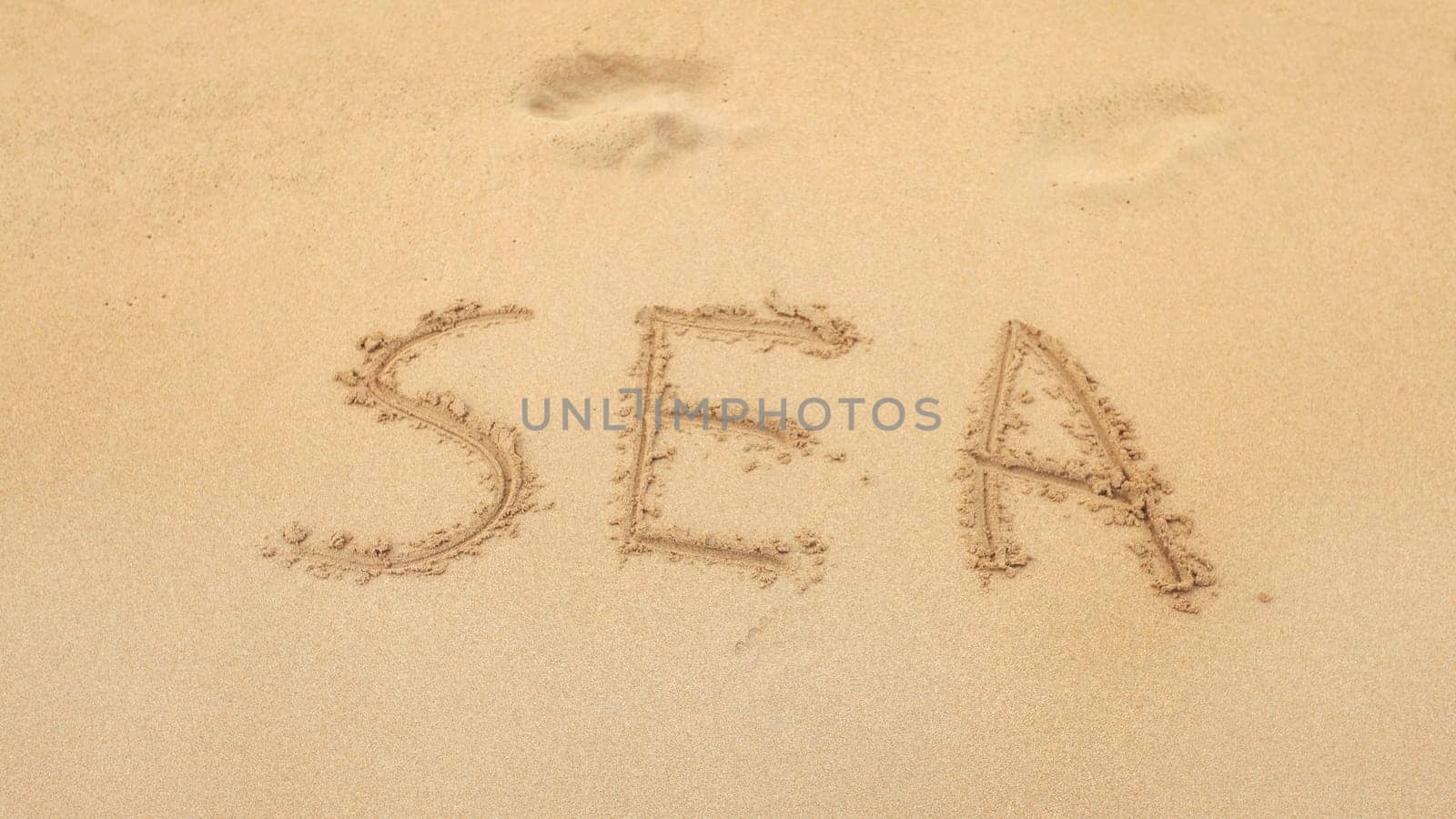 Word SEA written on wet beach sand.
