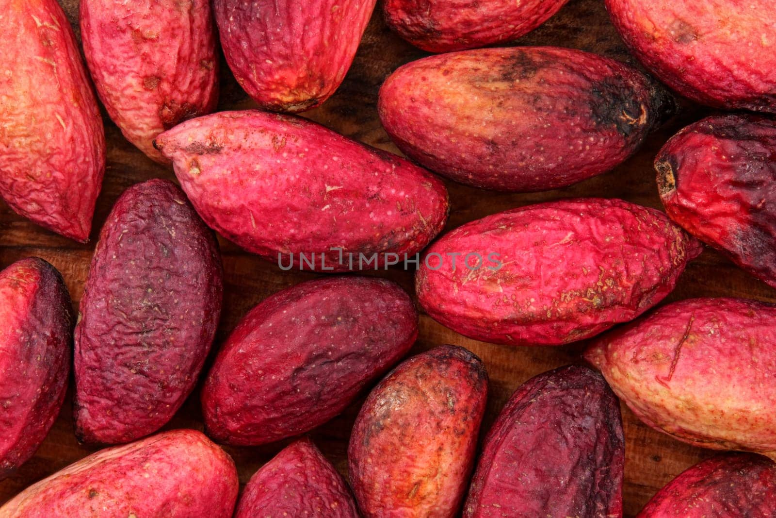 Top view closeup of raw turkish red pistachios, skin wrinkled after couple of days. Nuts and green seeds are under.