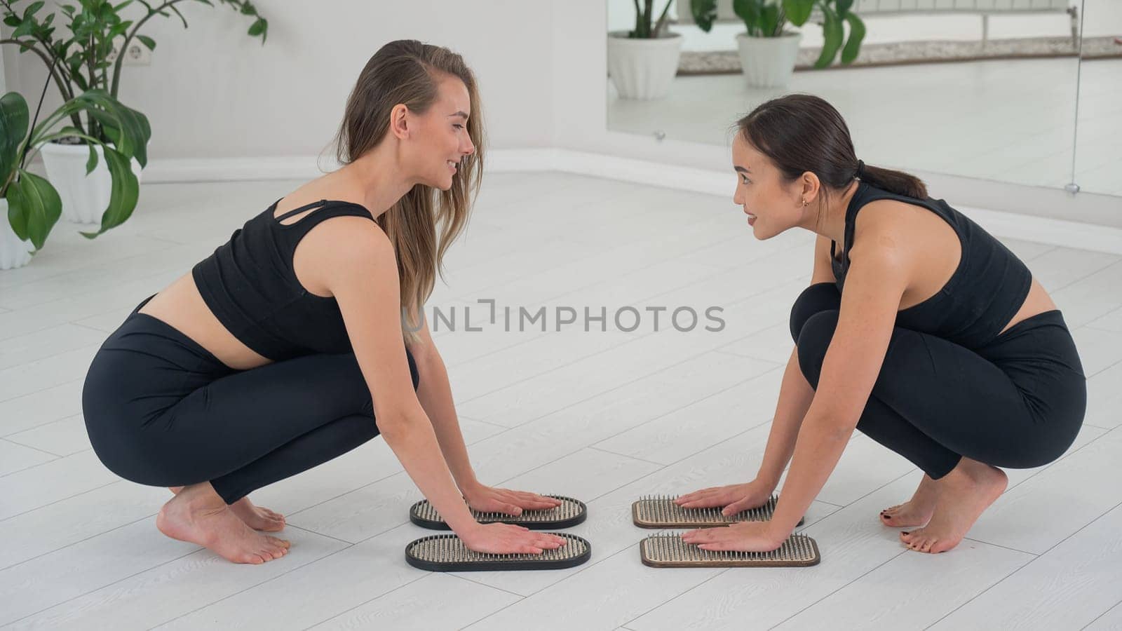 Caucasian and Asian women keep their hands on sadhu boards. Nailing practice