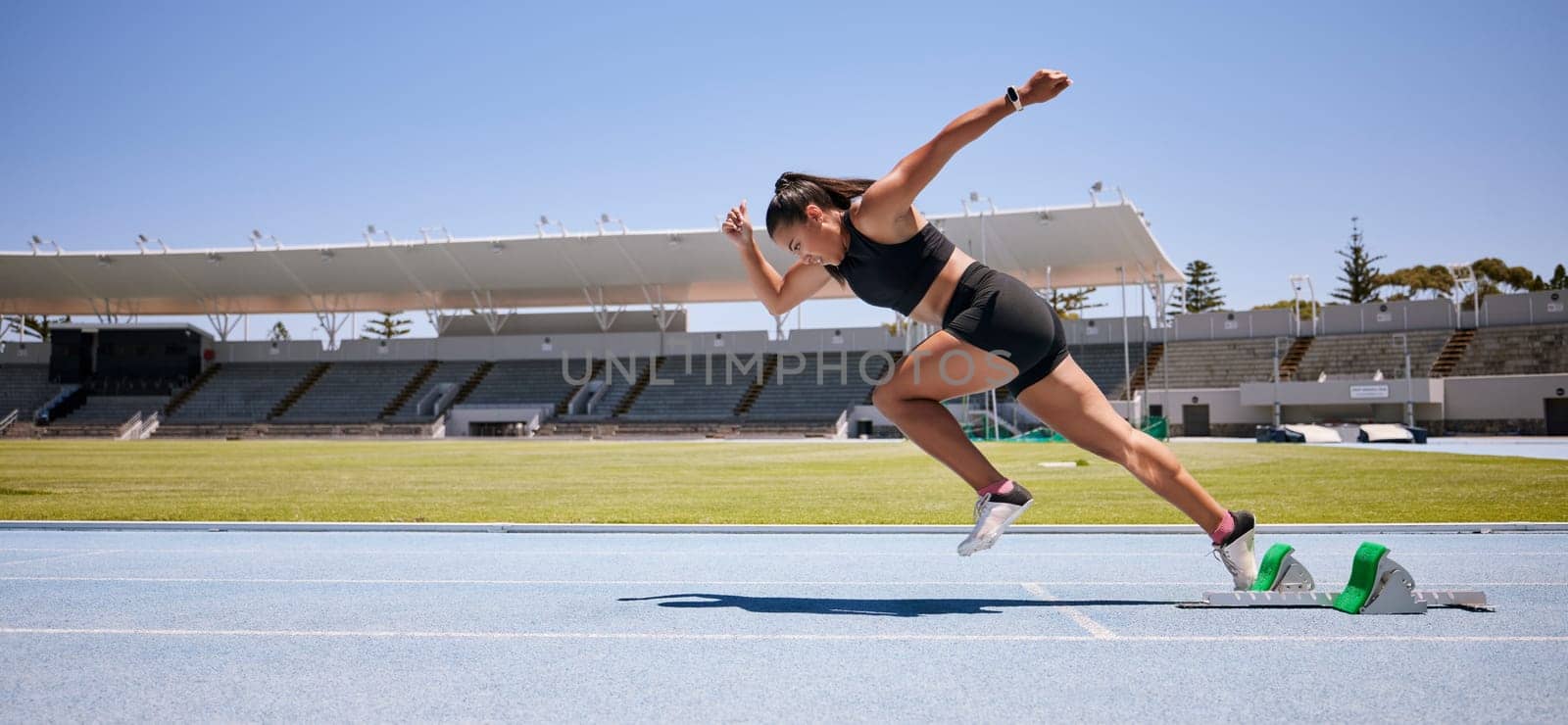 Fitness, start and running with woman in stadium for sports, training and marathon on race track. Fast, action and cardio with runner of competition field for speed, energy and endurance performance.