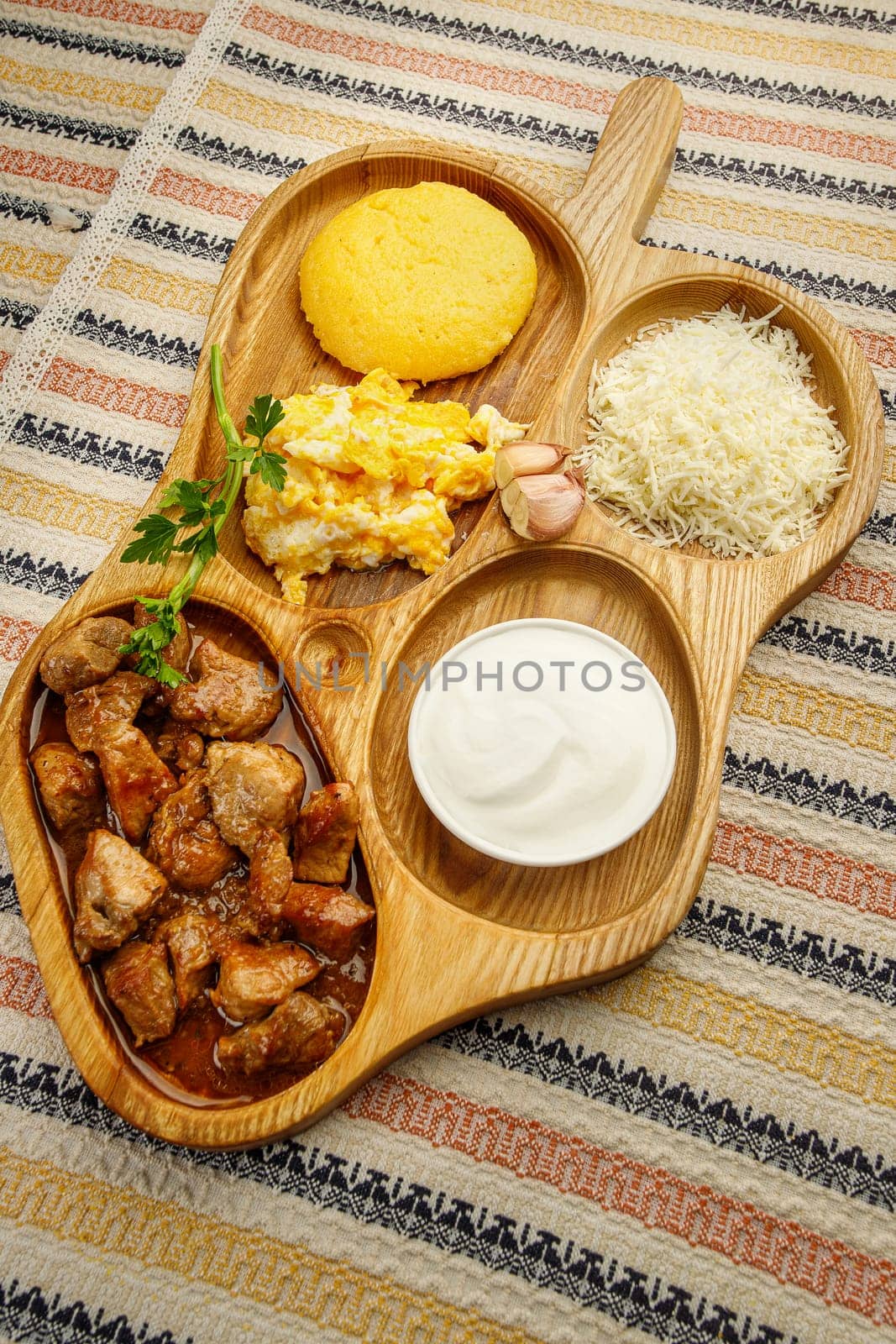 Tochitura is a traditional Romanian dish made from beef and pork with polenta, served on a wood decorative plate.