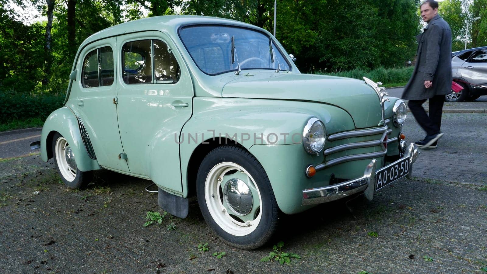 Amersfoort, the Netherlands May 21 2023 A man walks past a light blue very old Renault 4CV that is parked.. This kind of car was produced between 1947 and 1961