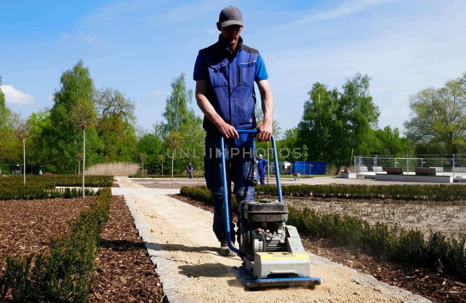 Bad Bentheim, Germany - May 5 2023 An employee of a landscaping company vibrates the sand from a new path with a compactor
