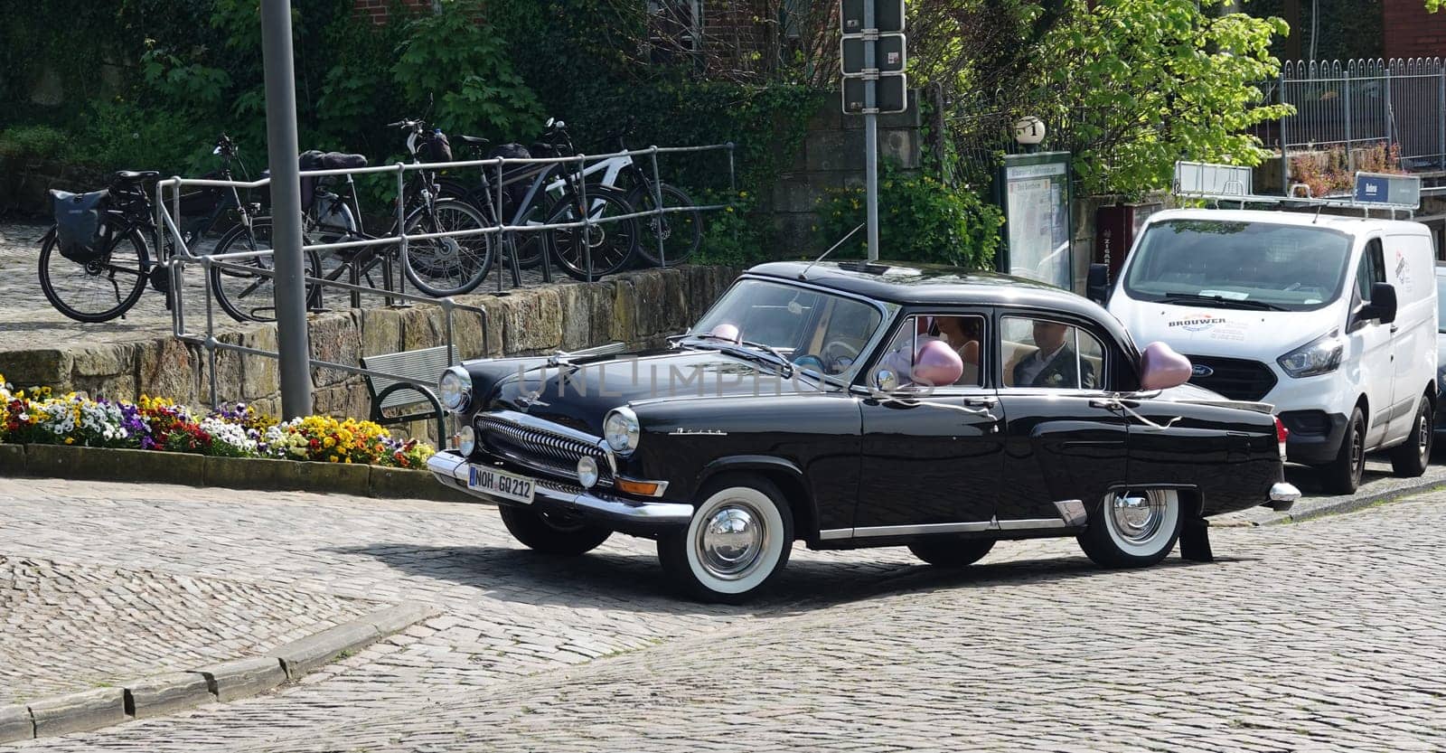 Bad Bentheim, Germany - May 5 2023 A couple is driven to their wedding ceremony in a black old-timer from Russia. The car is a GAZ Volga 2nd generation: the Shark with a jumping deer on the hood