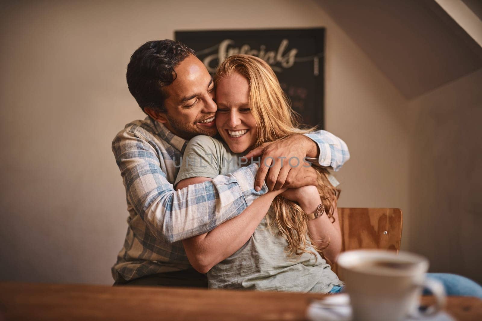 Love, couple and quality time at a cafe, hug and happiness together, romance and celebrate achievement. Valentines day, man and woman with smile, romantic and in coffee shop for break, relax or happy by YuriArcurs