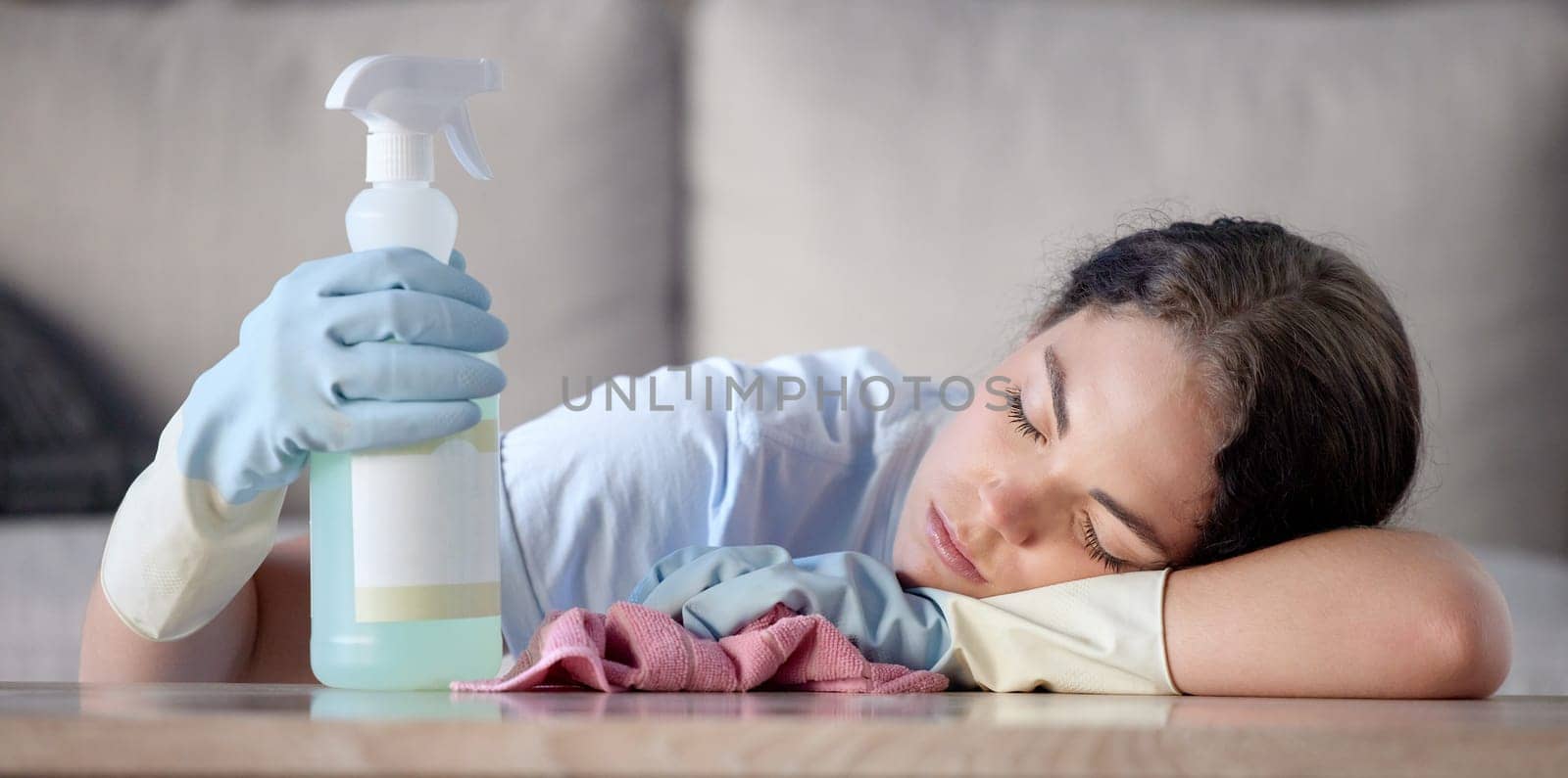 Tired woman, housekeeping and sleeping on table with detergent bottle by the living room sofa at home. Female exhausted from spring cleaning, burnout or nap after disinfection with sanitizer bottle.