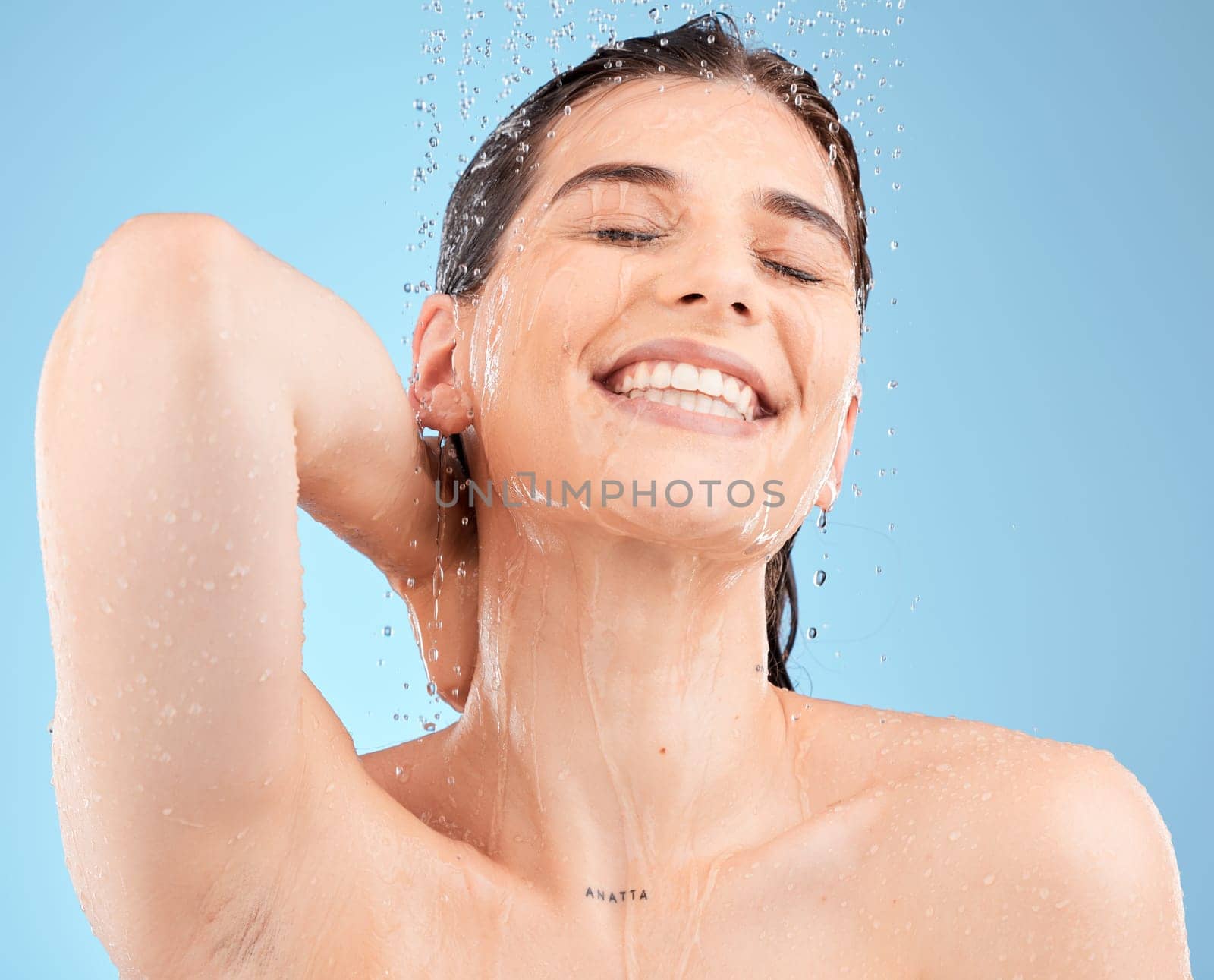 Water, skincare and beauty with woman in shower for cleaning, cosmetics and luxury. Self care, hygiene and hydration with girl model washing for health, wellness and relax in blue background studio.