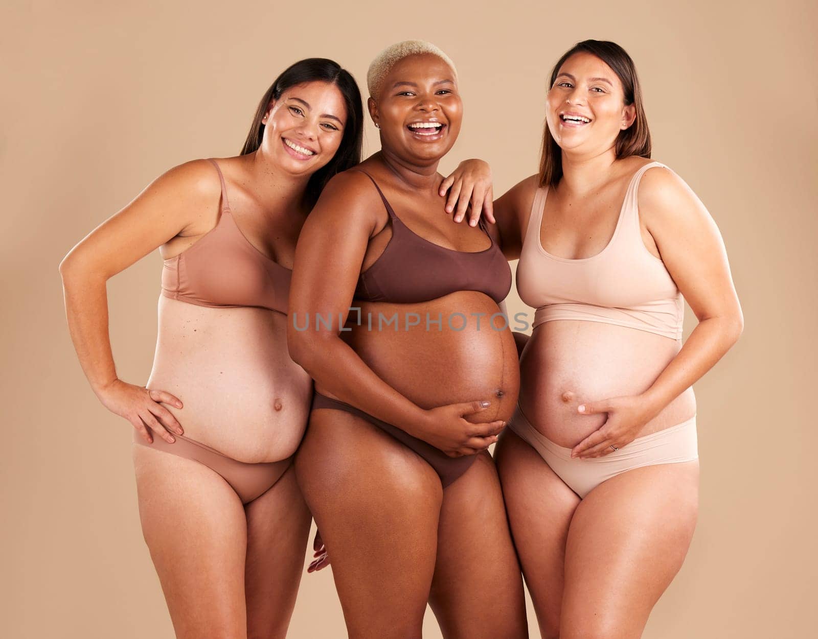 Portrait, beauty and laugh with pregnant friends in studio on a beige background for diversity or motherhood. Family, love and pregnancy with a woman friend group showing their baby bump stomach.