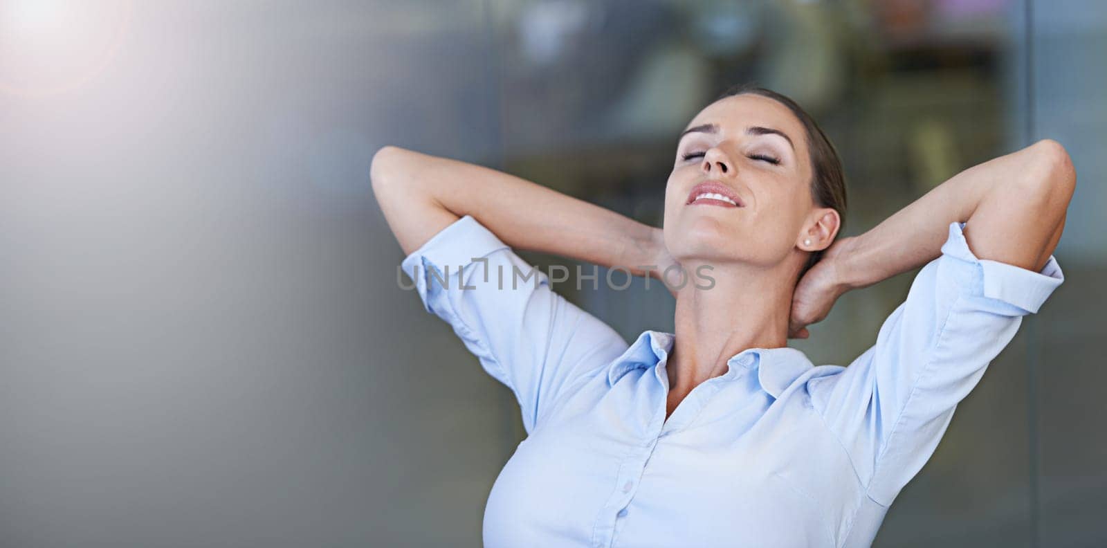 Taking a work timeout. A young businesswoman looking relaxed with her hands behind her head. by YuriArcurs