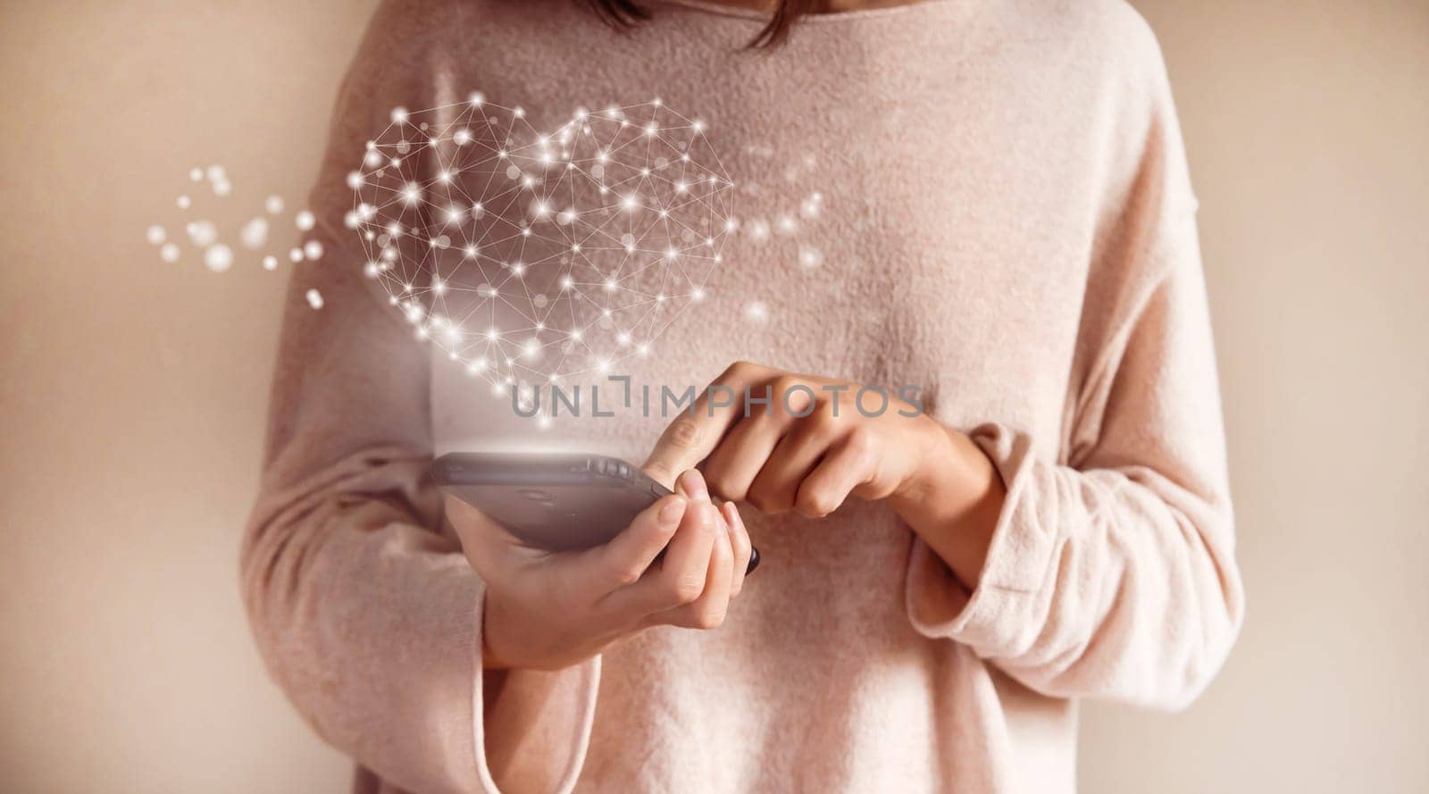 Young girl holds a phone in her hands, sends hearts to friends and family, closeup view of hands and a drawed glowing bright heart. A woman rates an application, searches for relationships online.