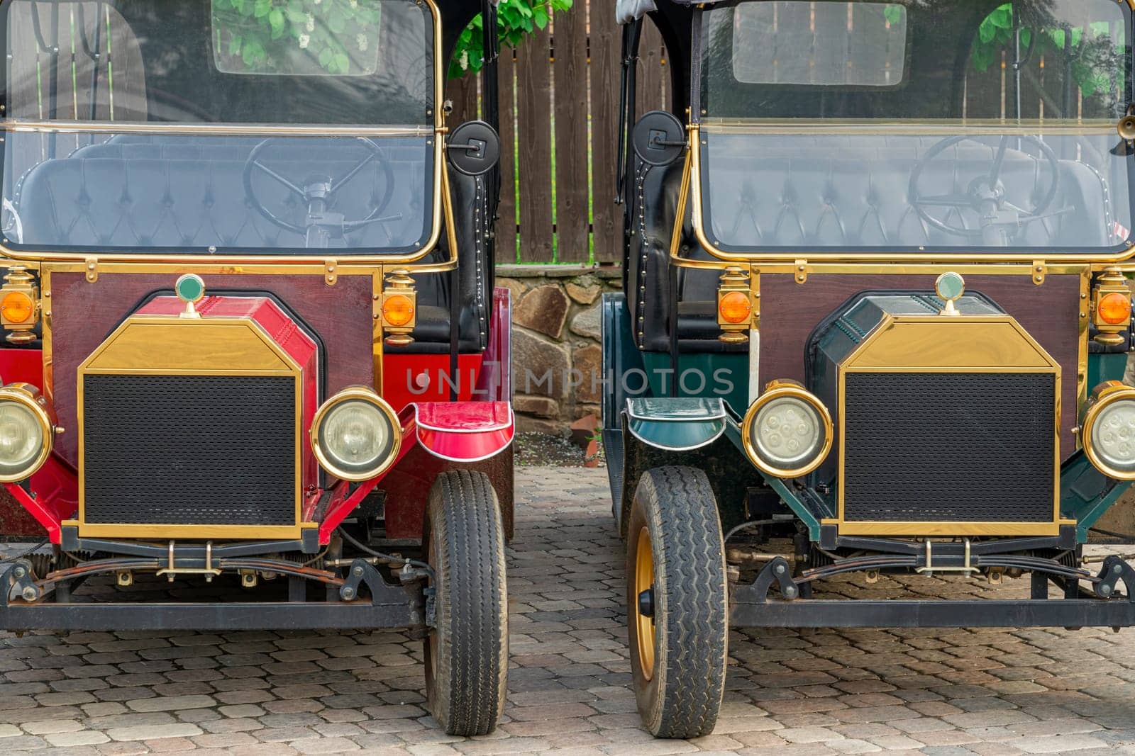 two retro cars close-up on the background of a wooden fence. photo