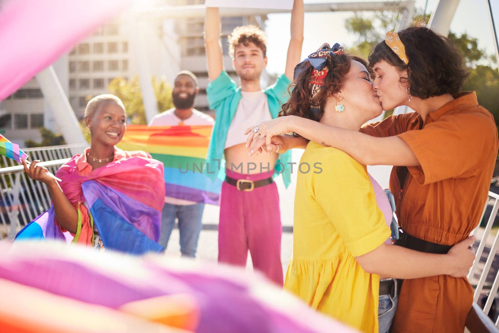 Lgbt, kiss and couple of friends in city with rainbow flag for support, queer celebration and relationship. Diversity, lgbtq community and group of people enjoy freedom, happiness and pride identity.