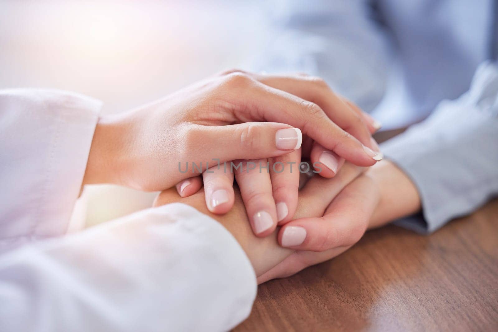 Holding hands, doctor and patient at desk for comfort, talking and communication for bad news, mental health or support. Therapist woman, cancer and together for empathy, care or wellness in hospital by YuriArcurs