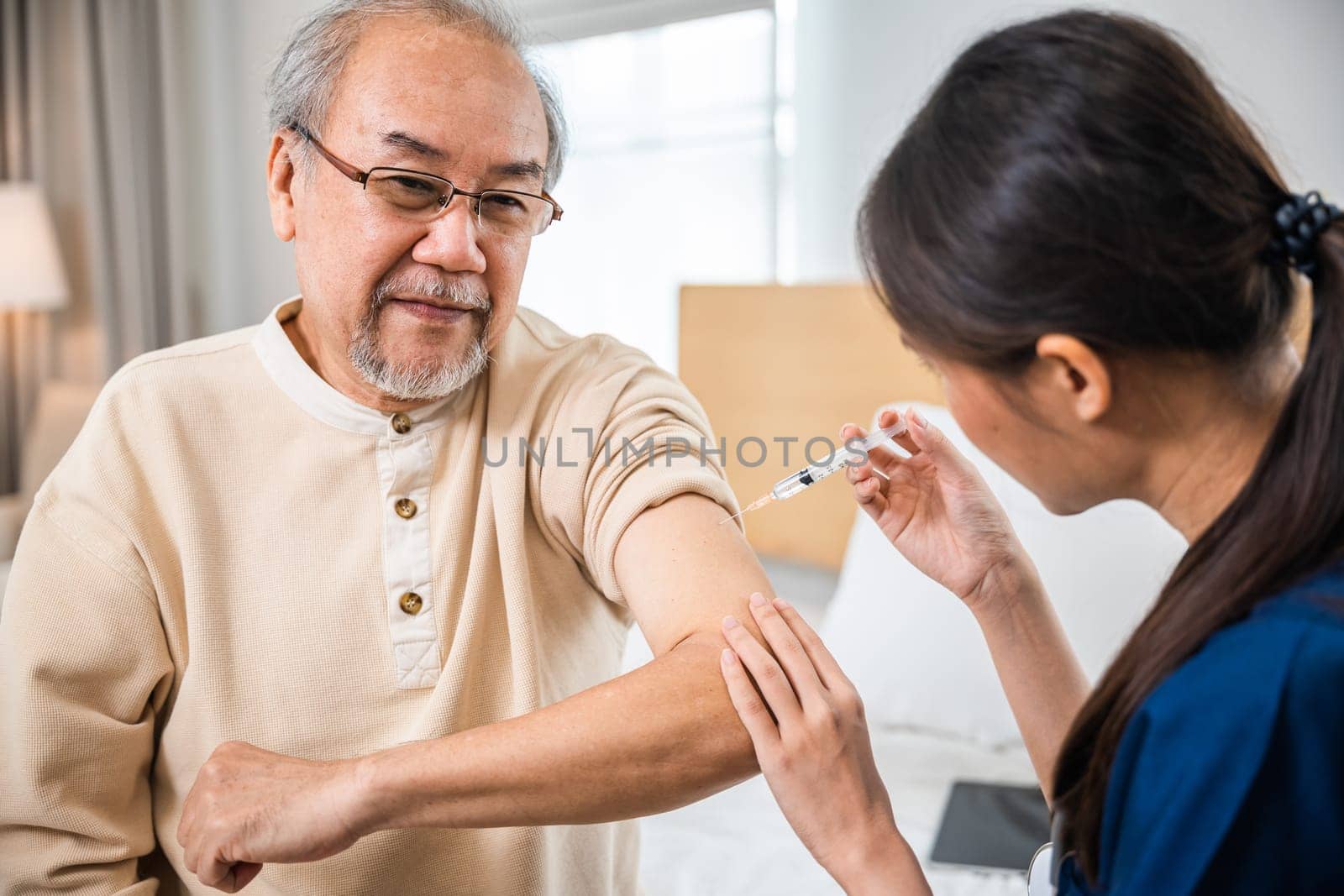 Doctor giving injection with syringe to retired senior man at clinic or hospital by Sorapop