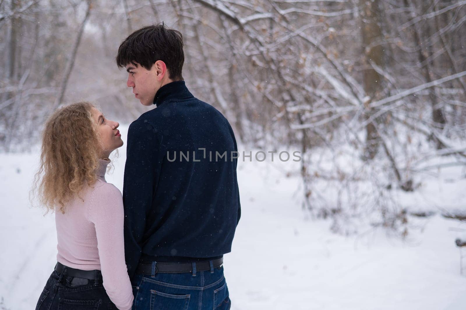 A young couple walks in the park in winter without jackets. Boy and girl hugging on the street. by mrwed54