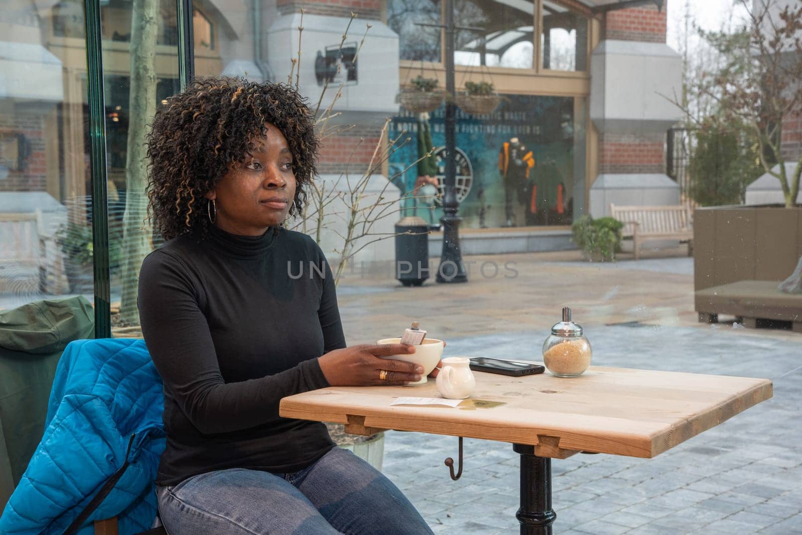 African young woman without makeup sits in a cafe in the morning, having just woken up, and drinks coffee, High quality photo