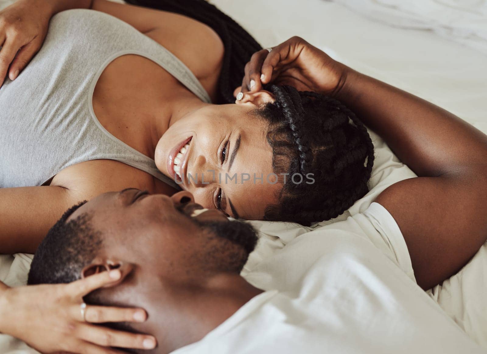 Couple, face and smile in bedroom, morning and love on bed with bonding, care and romance in home. Black couple, eye contact and touch with happiness, holiday or vacation in hotel, room or apartment.