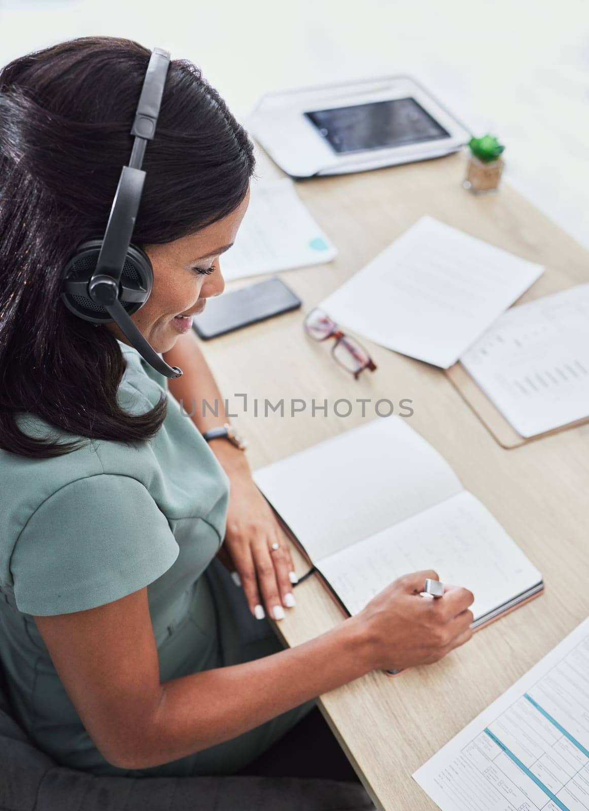 Customer support, call center and black woman writing in notebook for schedule, planning and feedback. Contact us, receptionist and female consultant in customer service, help desk and telemarketing.