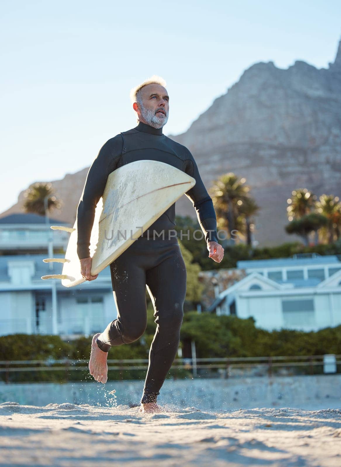 Beach, mature surfer running with surf board on sea sand and weekend water sports. Freedom, fitness and fun summer retirement holiday in Australia. Health, wellness and senior man on surfing vacation.