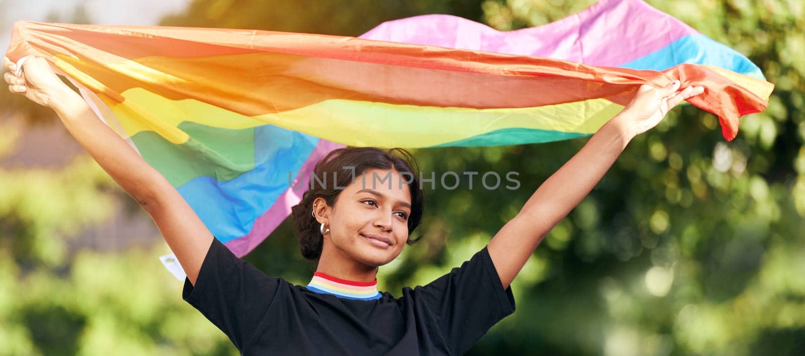 Rainbow, flag and gay pride with an indian woman in celebration of lgbt human rights alone outdoor. Freedom, equality and lgbtq with a happy female outside celebrating her equality or inclusion.