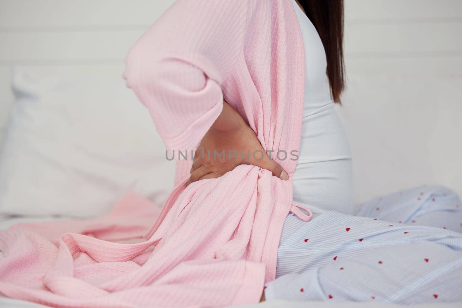 Tired, healthcare and pregnant woman with back pain on a bed for rest, break and maternity leave. Sick, injury and girl with backache, fatigue and stress during pregnancy in a bedroom for motherhood by YuriArcurs