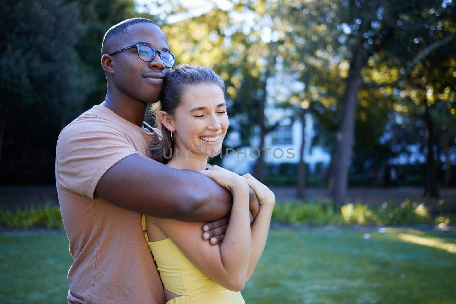 Summer, love and mockup with an interracial couple bonding outdoor together in a park or garden. Nature, diversity and romance with a man and woman hugging while on a date outside in the countryside by YuriArcurs