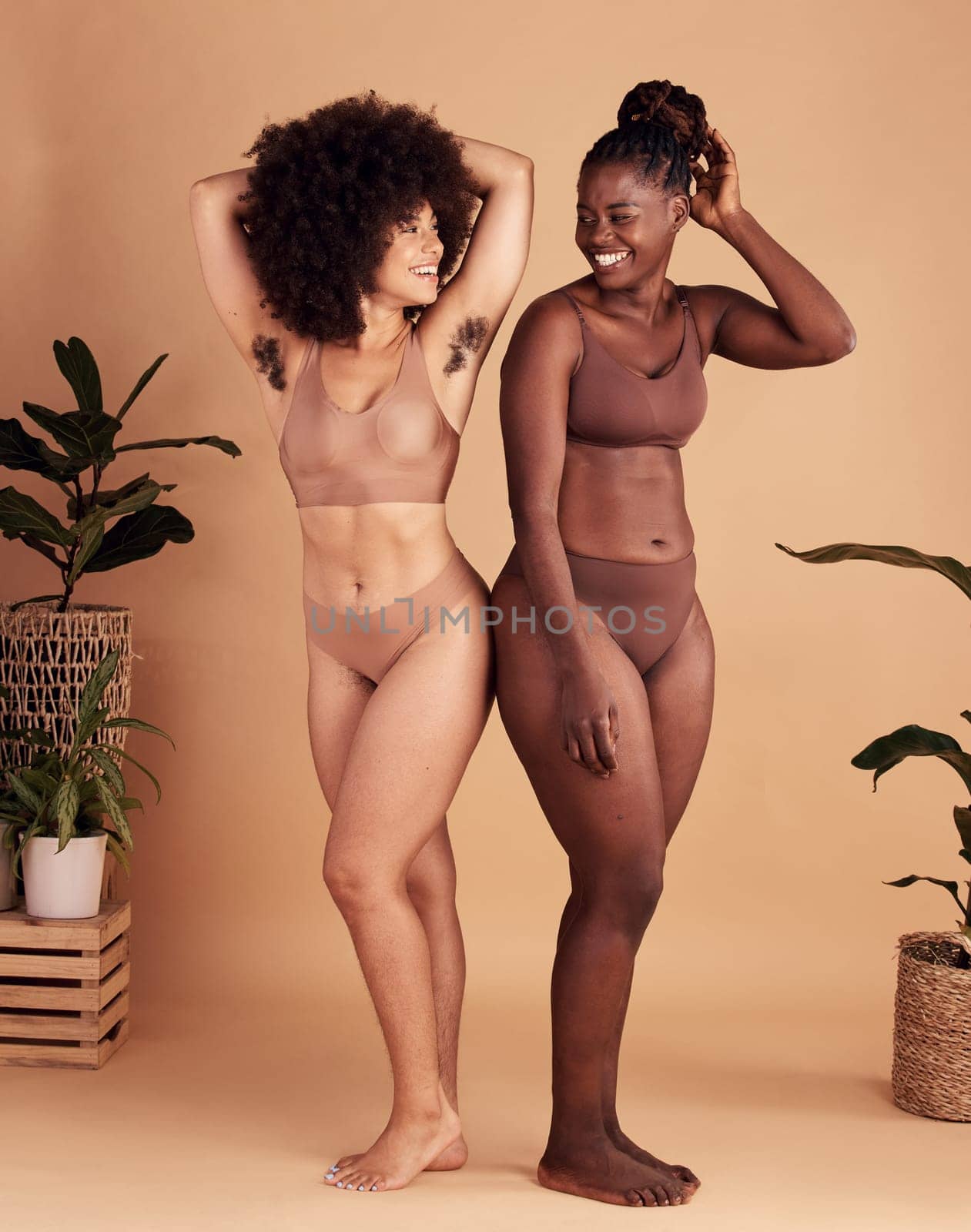 Diversity, body and natural with black woman friends in studio on a beige background for beauty or equality. Health, wellness and armpit hair with a model female and friend posing in underwear.