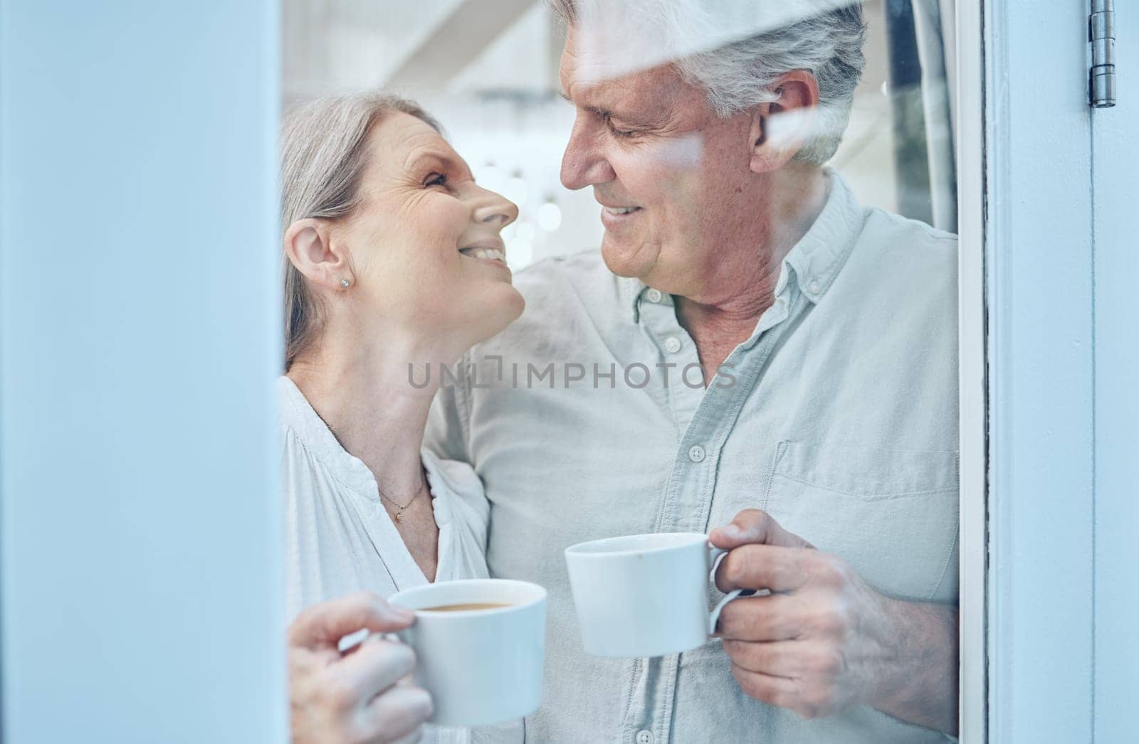 Retirement, coffee and love with a senior couple drinking or enjoying a beverage together in their home. Relax, romance and bonding with an elderly man and woman pensioner by a door in their house.