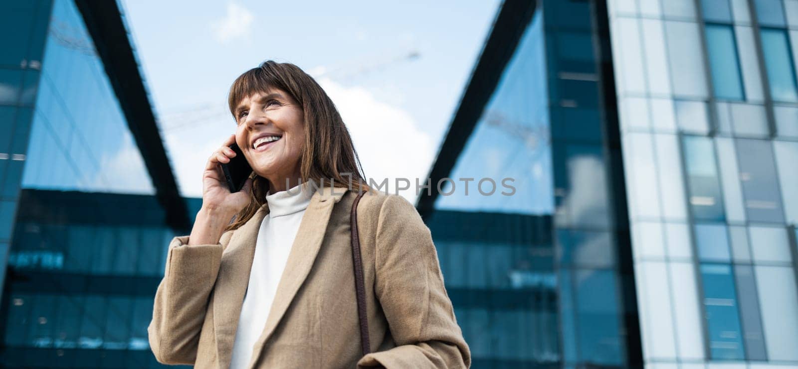 Business woman, phone call and smile for communication, networking and conversation with contact or investor outdoor by office buildings. Happy entrepreneur with smartphone with 5g network connection by YuriArcurs