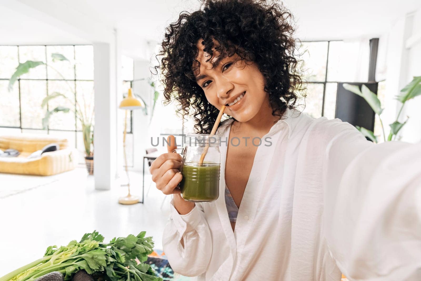 African american woman taking selfie drinking green juice reusable bamboo straw by Hoverstock