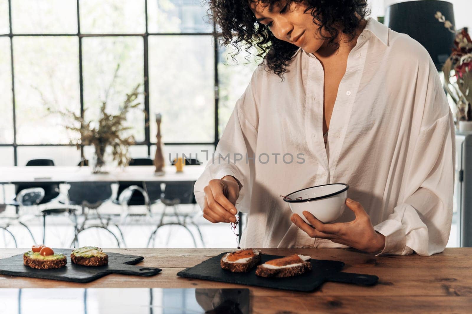 Young african american woman preparing smoked salmon toast for breakfast on wood kitchen counter top. Healthy lifestyle concept. Home concept. Copy space