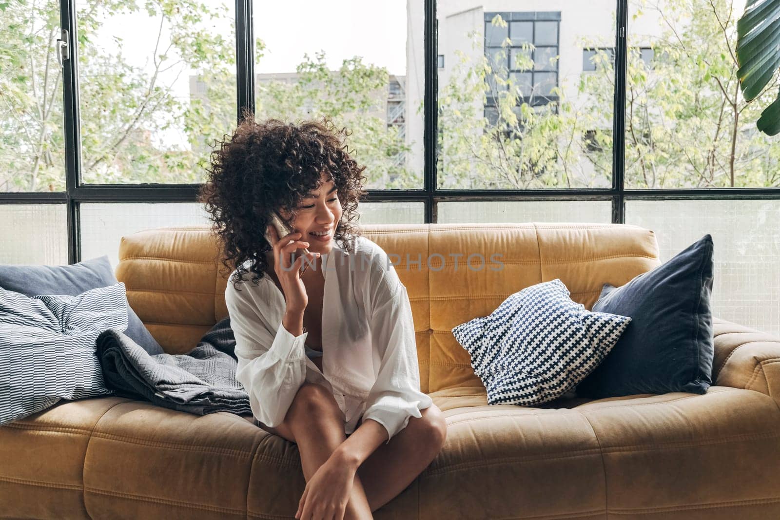 Young african american woman sitting sofa talking with a friend on cellphone at home. home concept. Technology concept. Friendship concept.