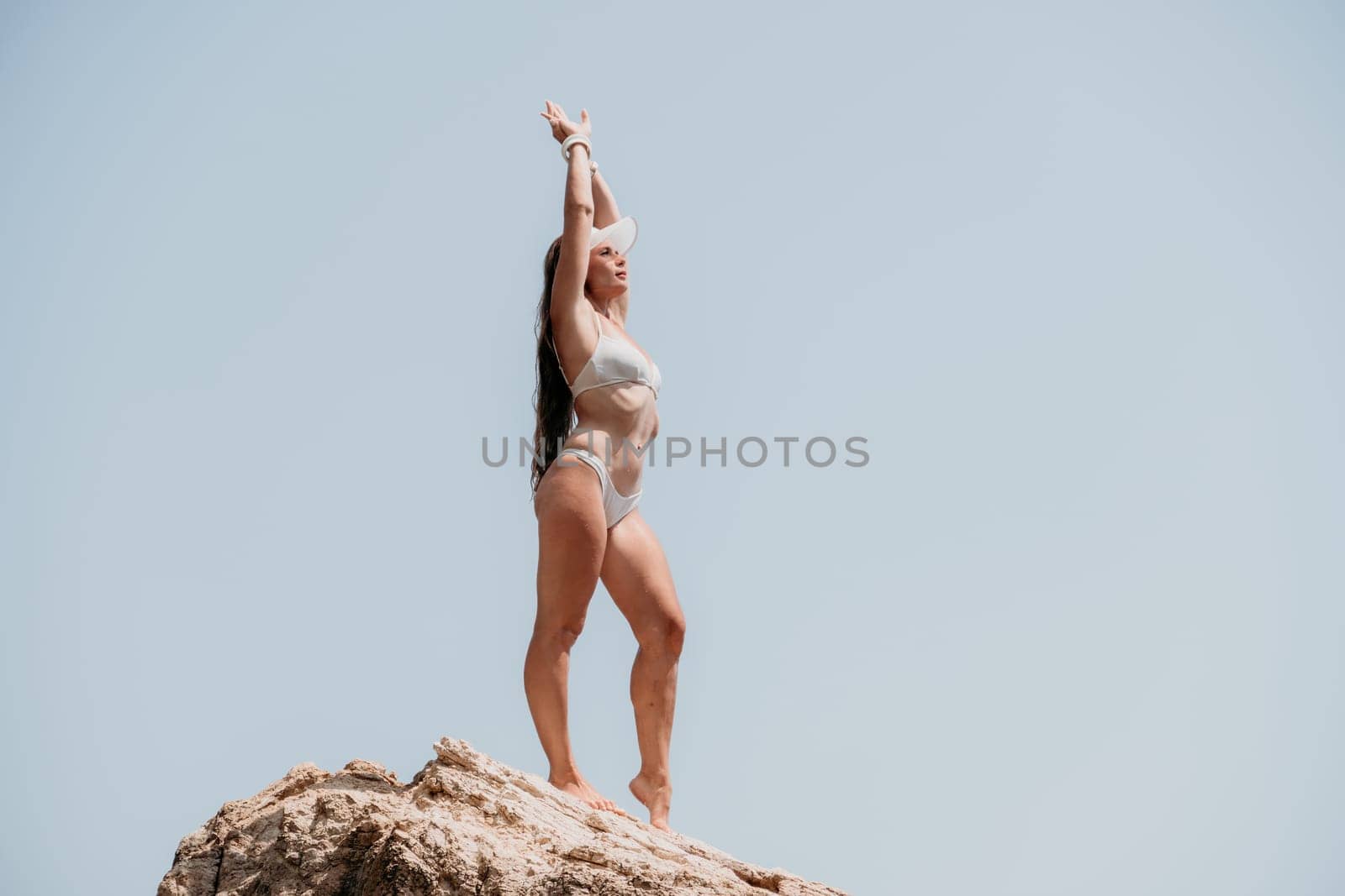 Woman sea yoga. Back view of free calm bliss satisfied woman with long hair standing on top rock with yoga position against of sky by the sea. Healthy lifestyle outdoors in nature, fitness concept. by panophotograph