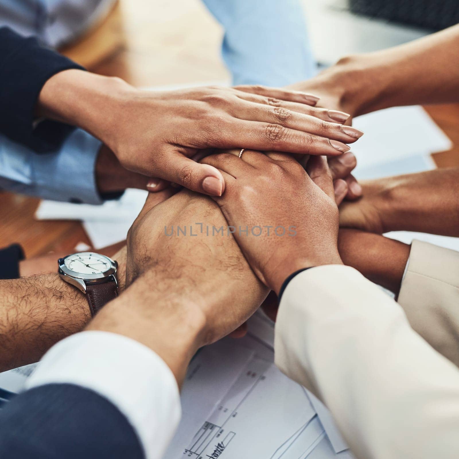 Closeup of hands together, business people in meeting and solidarity, support and team huddle with collaboration. Group of employees working, teamwork and mission with hand stack over paperwork.