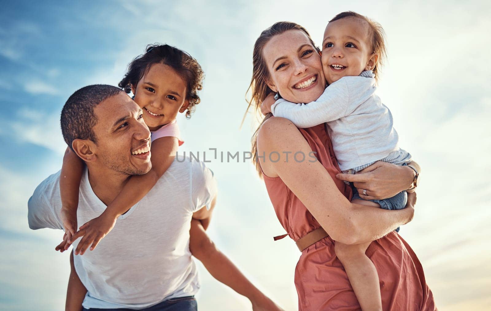 Happy family, blue sky and ocean, piggy back and hug for couple with kids on summer holiday at beach. Love, family and fun, man and woman smile with children sea for vacation time together at sunset