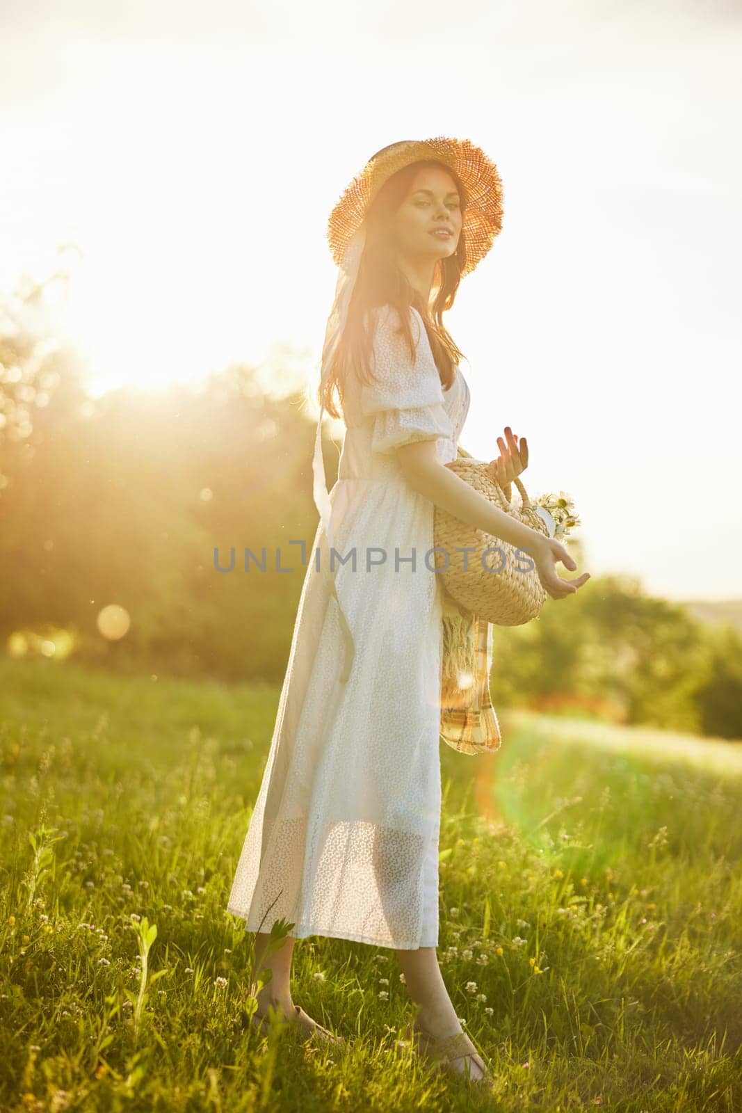 a woman in a light dress walks in the countryside in the rays of the setting sun. High quality photo