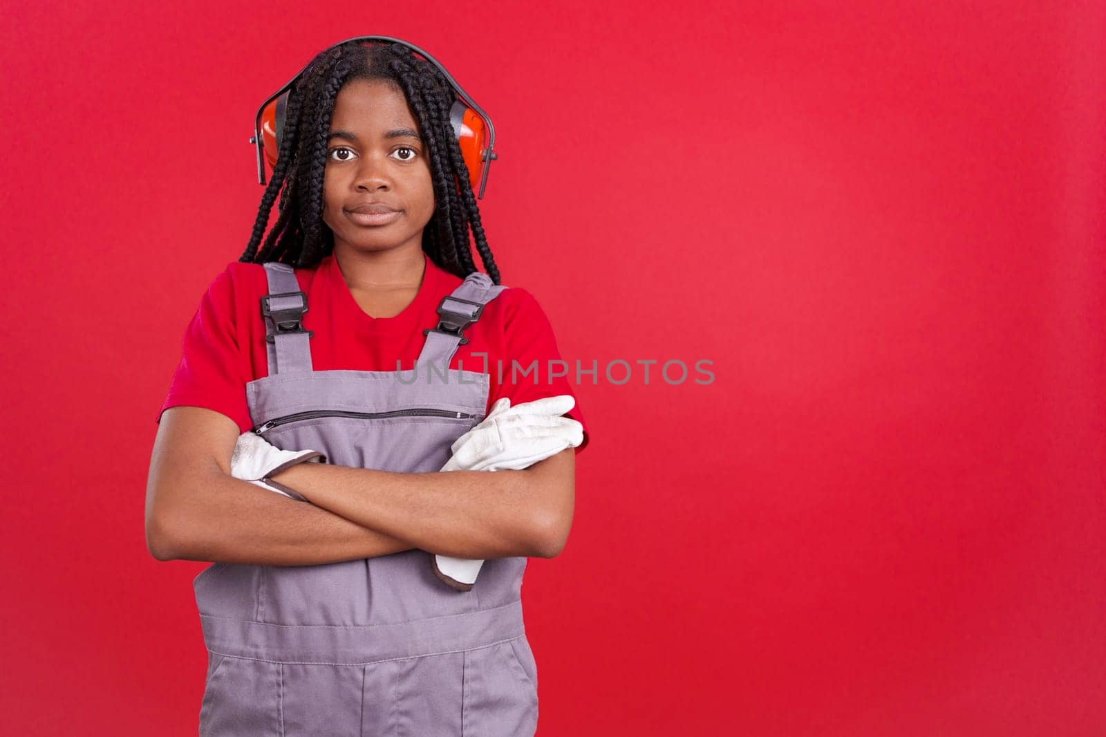 Friendly african woman carpentry worker in work uniform in studio with red background